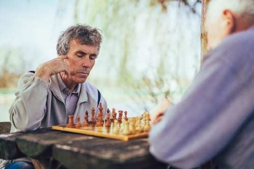 Two senior men sitting outside playing chess