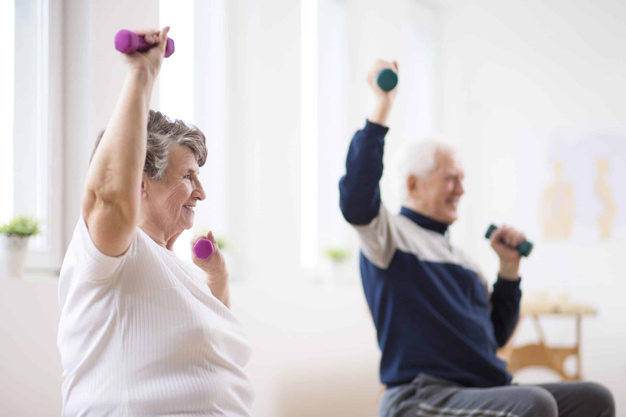 Two seniors lifting hand weights while seated